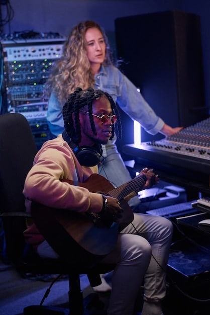 A diverse group of musicians and producers in a modern recording studio, actively collaborating around a mixing console and computer screens, indicating teamwork in music creation.