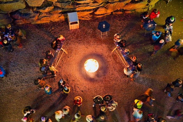 An aerial shot of a Survivor tribal council set at dusk, with contestants seated around a fire pit, symbolizing the intense competition and dramatic eliminations characteristic of the genre.