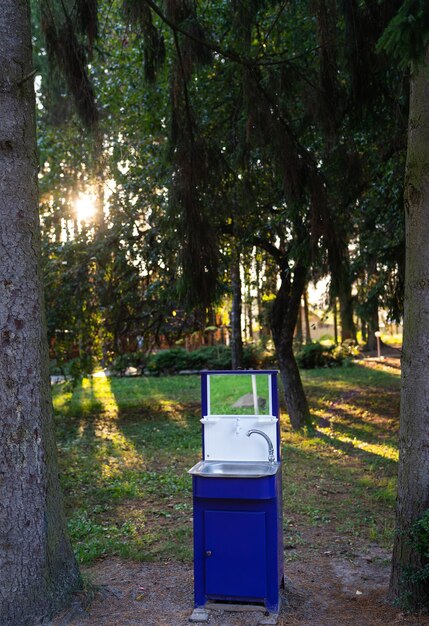 A theme park employee sorting waste into clearly marked recycling bins with a futuristic, eco-friendly design, set against a backdrop of lush green landscaping and solar panels on rooftops.