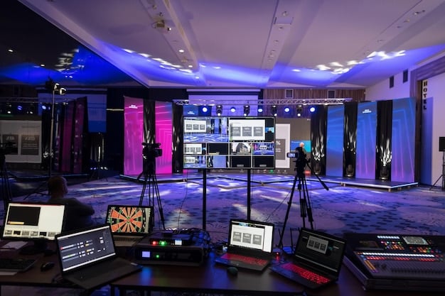A broadcast studio setup for an eSports tournament, with commentators in front of screens displaying game statistics and live gameplay, surrounded by professional lighting and sound equipment.