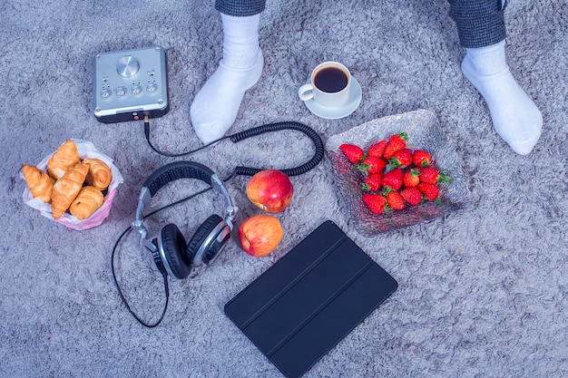 A neatly arranged side table next to a sofa, showing a full water bottle, a small bowl of pre-cut fruit, a remote control, and a charging phone, indicating preparation for a long viewing session.