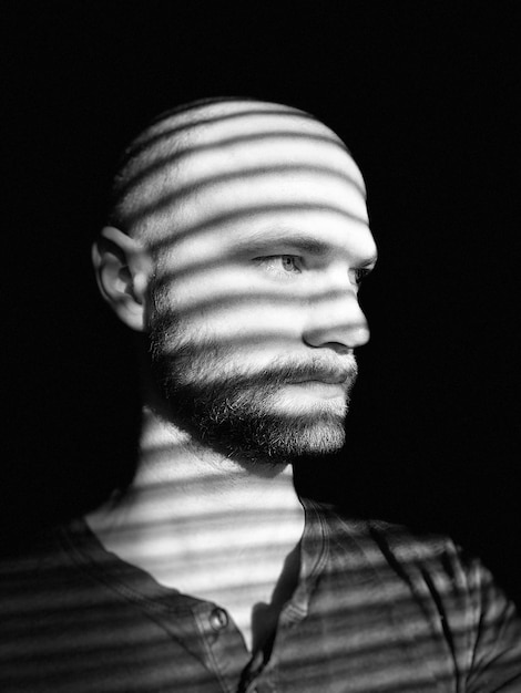 A person's introspective face, partially obscured by shadows, with a subtle look of contemplation mixed with intensity, perhaps reflecting on a dark or challenging thought. The background is blurred, suggesting a focus on internal processing.