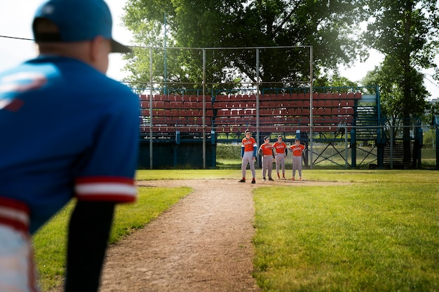 A bustling youth baseball tournament with multiple games simultaneously underway on well-maintained fields. Families are seated in bleachers, and concession stands are visible in the background, signaling community activity.