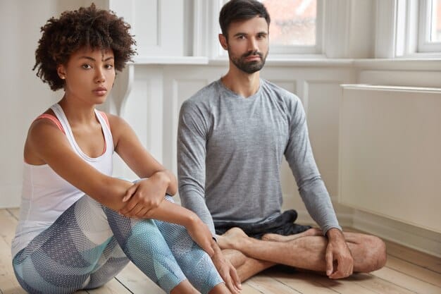 A sports psychologist or coach guiding an athlete through a breathing exercise, demonstrating a calm, focused environment during a training session. The athlete appears receptive and engaged.